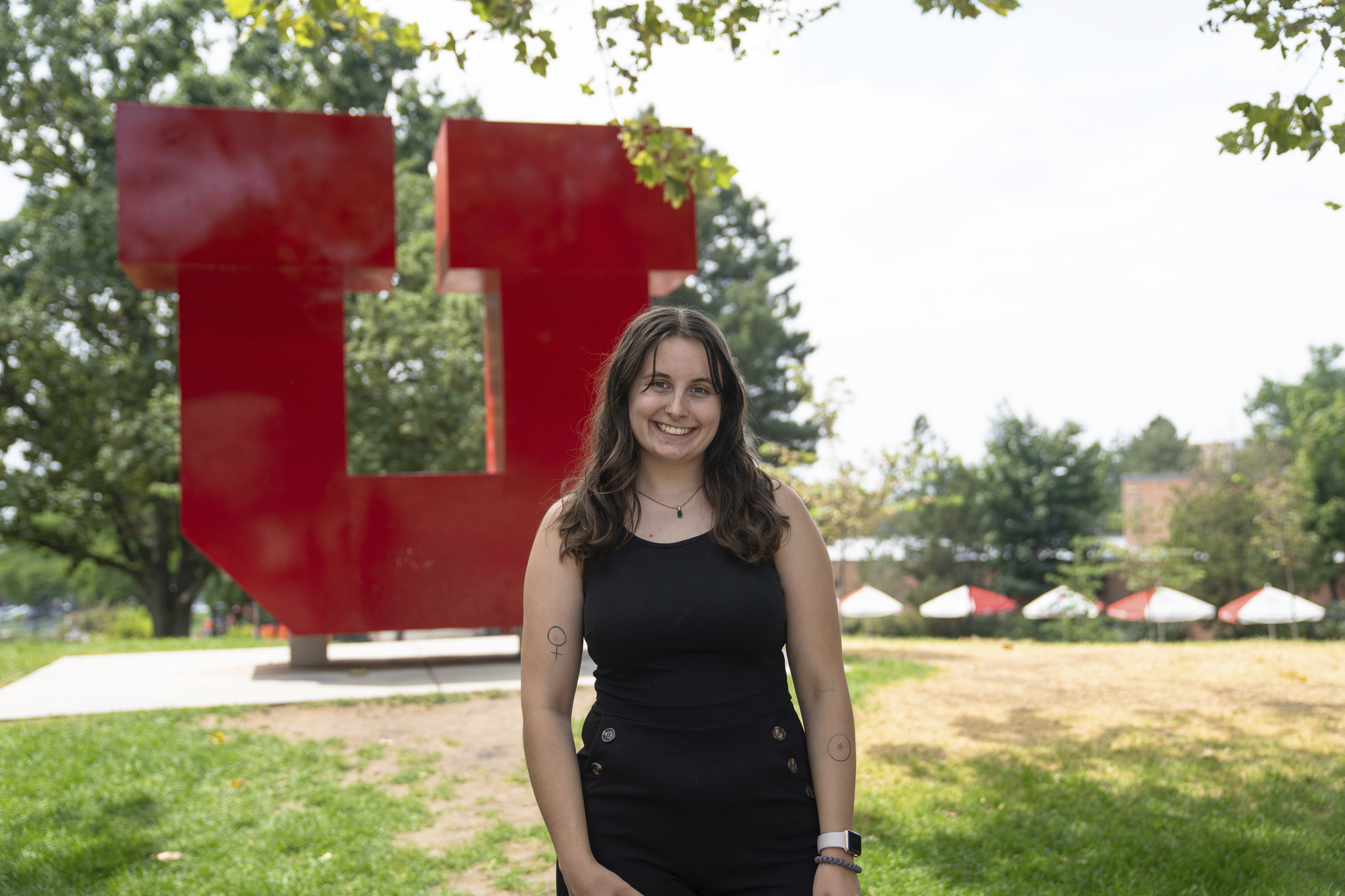 Student stands in front of red block U statue 