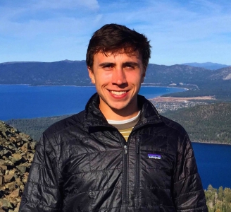 Man in front of water and mountains